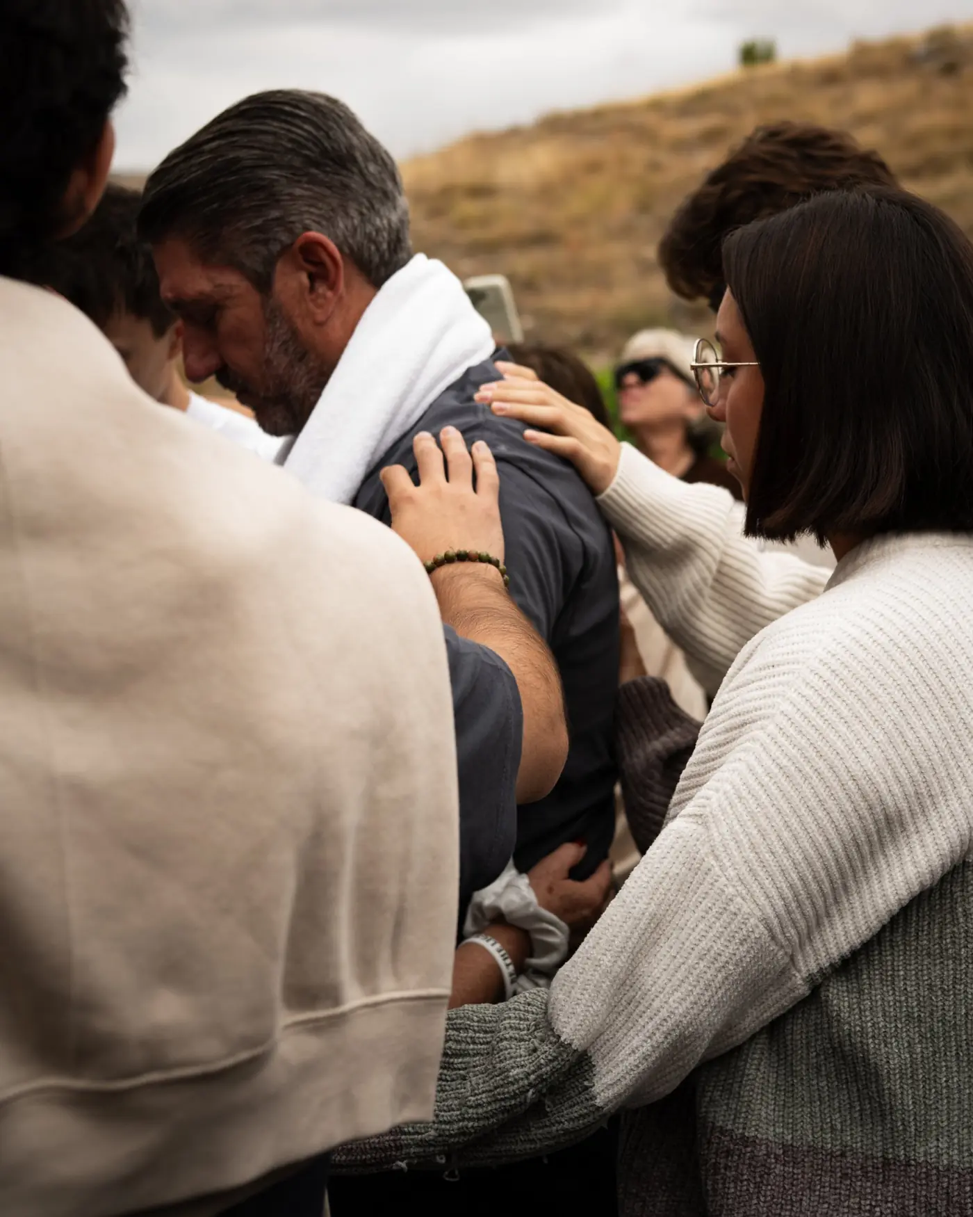 Varias personas de la comunidad oran juntas por un hombre durante un retiro
